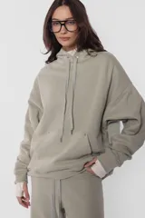 Buzo hoodie de frisa color beige, de silueta oversize, con puños y cintura de rib al tono, capucha forrada en su interior, bolsillo canguro, cordones con ojalillos y punteras metálicas personalizadas con marca, tanca para regular cordones, remaches en boca de bolsillo y bordado en espalda a contratono.