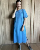 Vestido midi negro con cuello redondo y mangas cortas. Presenta dos bolsillos cuadrados en el pecho y ribetes blancos en cuello, mangas, bolsillos y ruedo.