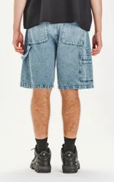 Bermuda de denim celeste con calce oversize, estilo carpintero y proceso de efecto desgaste.