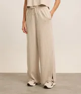Conjunto deportivo de dos piezas color beige con finas rayas verticales negras. Incluye un chaleco corto con cuello en V y un pantalón palazzo con cintura elástica ajustable.