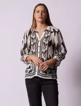 Blusa de gasa estampada marca Figueroa & Flower, color blanco con estampado abstracto en negro. Tiene cuello a la base con escote en V, apertura central con botones y mangas largas ¾ amplias.