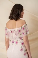 Vestido largo de tul bordado en color rosado, con flores bordadas en tonos fucsia y rosado en la parte superior, tajo lateral y mangas caídas.