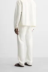 Pantalón de jean blanco, corte recto, con bolsillos frontales y traseros tipo parche.