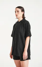 Camisa negra de manga corta con textura y cuello clásico.