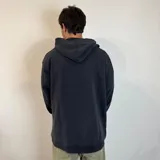 Canguro negro con capucha, corte oversize, bolsillo tipo canguro y logo blanco estampado en el pecho.