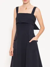 Vestido midi rojo de poplin con lycra, corte evasé, breteles anchos, bolsillos laterales y tajo frontal. Se ajusta en la espalda con un lazo.