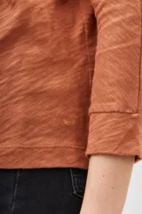 Remera de manga larga color terracota con textura jaspeada, confeccionada en algodón peruano. Presenta un calce holgado con mangas que se ensanchan debajo del brazo y se ajustan en la muñeca.