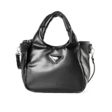 Cartera negra de cuero sintético con doble asa, una corta fija y otra larga extraíble. Tiene cierre principal con cremallera y broches magnéticos, tres compartimentos internos, un bolsillo con cremallera y otro abierto. El logo de la marca es un triángulo metálico plateado.