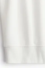 Buzo blanco de corte holgado con cuello redondo y puños y ruedo acanalados. Estampa frontal con la frase "Bisous Paris" en letras negras.