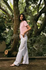 Chaqueta de punto color crema con cuello redondo, manga corta con volantes, bolsillos de plastrón y cierre frontal con botones metálicos.