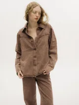 Campera de denim gastado color celeste, con cuello camisero, corte holgado y canesú con costuras delante y atrás.