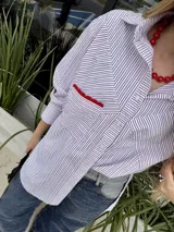 Camisa oversize a rayas verticales color blanco y marrón, con bolsillo en el pecho con detalle de bordado rojo.