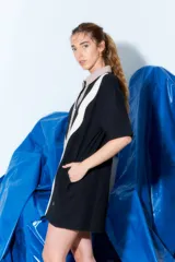 Vestido corto tipo túnica con cuello camisero, manga corta y cierre frontal con botones. Diseño con bloques de color verde, blanco y beige en patrón ondulado.