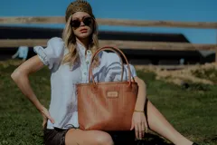 Bolso tipo tote de cuero color marrón con diseño tejido. Tiene bolsillo interno, porta llaves y cierre.