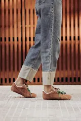 Zapatillas urbanas de cuero color tostado, con cordones verdes y suela de goma.