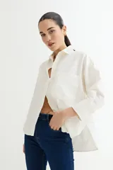 Camisa de manga larga color verde oliva, con cuello camisero y bolsillo de parche en el pecho. Presenta un corte holgado y tejido de apariencia rústica.