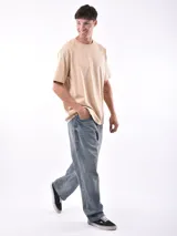 Remera gris de corte oversized, cuello redondo y mangas cortas. 
