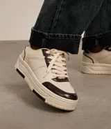 Championes urbanos de cuero sintético color crema con detalles en marrón.