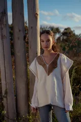 Chaleco tejido color crudo con aplique de cuero marrón en el cuello y detalle de pespunte en el contorno.