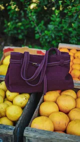 Bolso tote color morado de gamuza con doble asa corta y correa larga desmontable.