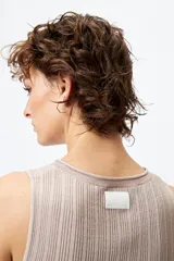 Musculosa de punto color beige, con textura acanalada y detalle de trenzado lateral ajustable.