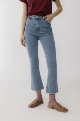 Pantalón jean cropped color celeste, de tiro alto, corte ajustado en la cadera y acampanado en la botamanga, con terminación desflecada.