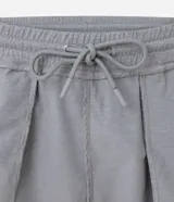 Bermuda deportiva gris de poliéster con cintura elástica y cordón interno ajustable. Cuenta con un bolsillo trasero funcional con cierre de cremallera.