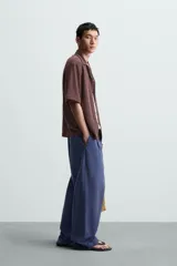 Camisa de manga corta con cuello bowling y calce relajado. Presenta un tejido con textura estructurada y efecto lavado, con cierre frontal de botones al tono.