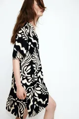 Vestido túnica corto de viscosa con estampado abstracto en blanco y negro, cuello mao con abertura en V, mangas cortas, corte holgado, hombros caídos y tajos laterales. Espalda ligeramente más larga.