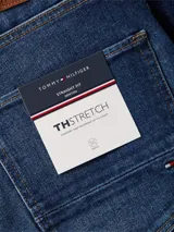 Pantalón de jean azul oscuro, corte recto, con cierre de botón y cremallera, y detalles distintivos de la marca Tommy Hilfiger.