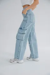 Pantalón de jean celeste, de tiro alto y corte ancho, con bolsillos cargo laterales y cierre con cremallera en los tobillos.