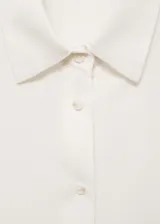 Camisa blanca de tejido fluido con cuello redondo y escote de pico.