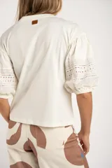 Remera negra de algodón con mangas 3/4 abullonadas con detalle de encaje calado. Corte al cuerpo.