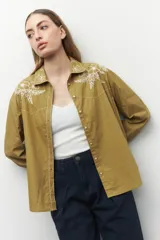 Camisa de manga larga color tostado, con bordado floral en el cuello y botones.