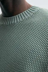 Sweater azul de punto con textura, corte holgado, cuello redondo y mangas largas con puños acanalados.