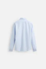Camisa celeste de algodón, corte regular fit, con cuello italiano, manga larga con puños abotonados y cierre frontal con botones.