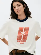 Remera color beige con cuello redondo azul marino y estampa geométrica en el frente con la inscripción "Athletic Club 1880".