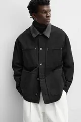 Parka negra de algodón con cuello solapa de cuero sintético, corte recto, acolchada y con cierre frontal de botones.