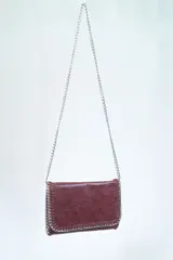 Bandolera negra con cadena plateada y pespuntes en los bordes.