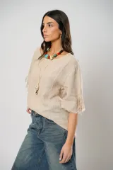 Blusa beige de lino con mangas 3/4 con lazos y detalle de flecos en los puños.