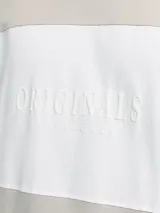 Camiseta de manga corta color beige con bloque central blanco con la palabra "Originals" en relieve.