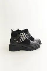 Botas cortas negras de cuero con punta cuadrada, detalle de hebilla metálica y suela track.