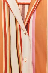 Camisa de manga larga con cuello solapa y cierre frontal con botones. Diseño a rayas verticales en tonos naranja, marrón, rosa y blanco.