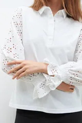 Camisa blanca de mangas largas con broderie y puños elásticos.