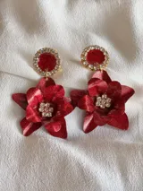 Par de aros colgantes con base circular dorada con strass y dije de flor roja con strass en el centro.