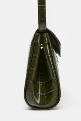 Bolso de mano alargado con acabado en relieve de cocodrilo, color verde oscuro brillante. Cuenta con asa de mano superior y un cierre frontal mediante clip metálico. Incluye un bolsillo interior con cremallera y un asa extraíble para usar como bandolera.