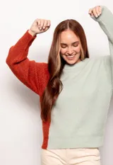 Sweater de punto color block, con un lado verde claro y otro lado naranja, de manga larga y terminaciones acanaladas en puños y cuello.