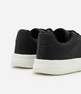Championes blancos de cuero sintético con cordones y suela gruesa.