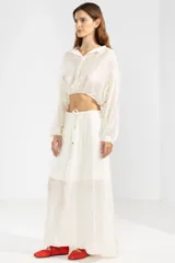 Blusa corta color crema en tejido arrugado liviano, con cuello mao, botones al frente y mangas abullonadas. Terminada con ruedo elastizado.