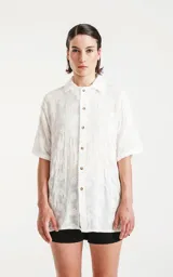 Camisa blanca con bordado de flores blancas, de manga corta y corte recto.